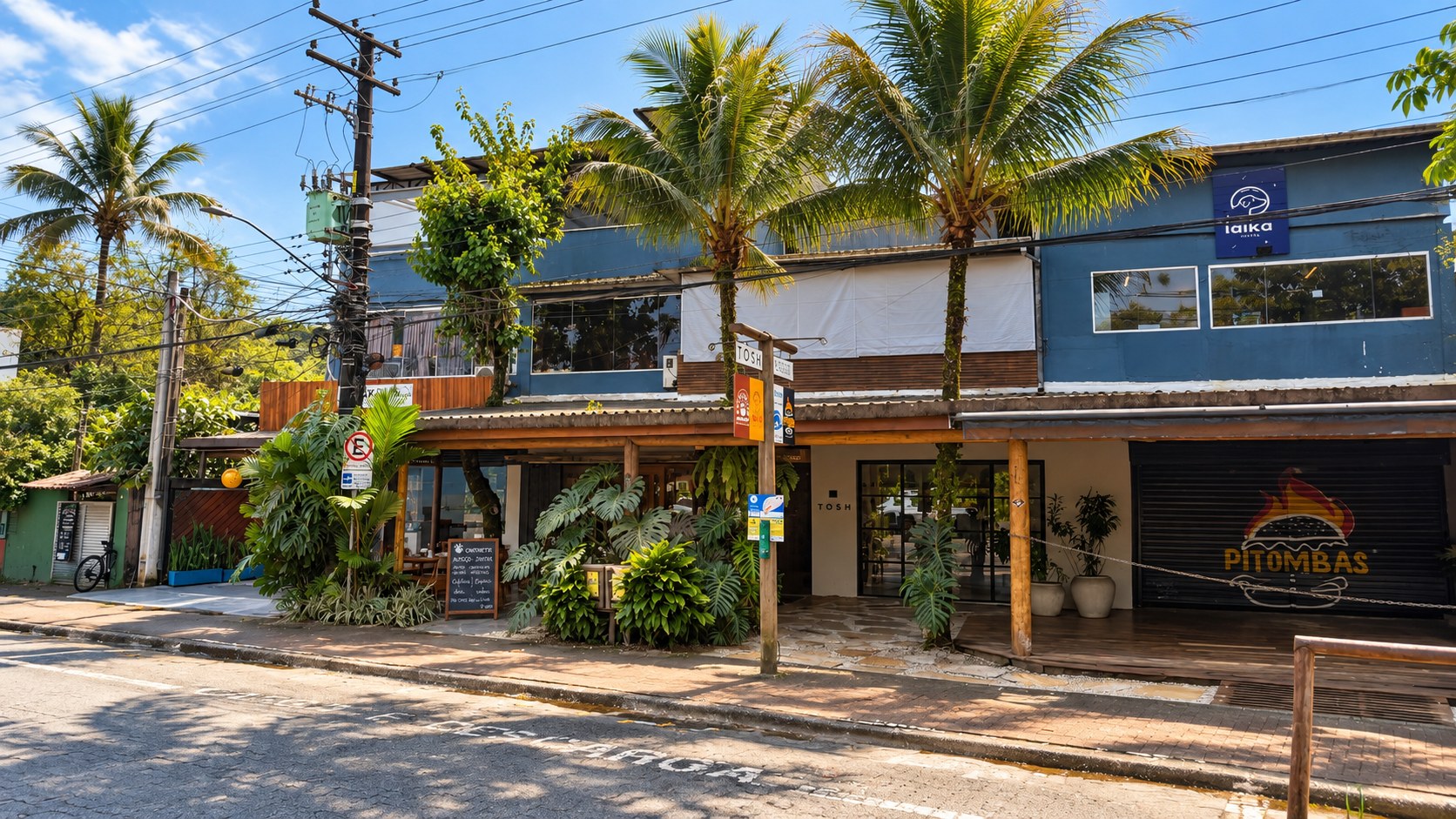Vista da rua em Camburi com coqueiros e a fachada da Cantinetta